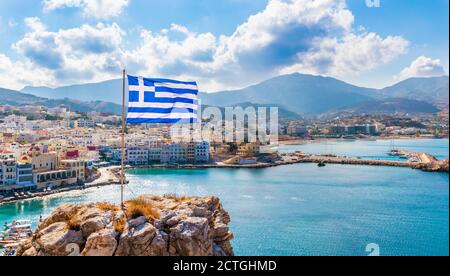 Vista panoramica della baia di Pigadia, città e porto con bandiera greca, isola di Karpathos, Grecia Foto Stock