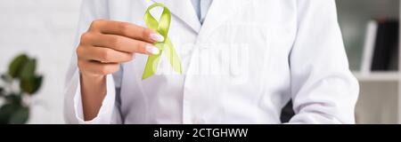 vista ritagliata del medico che tiene il nastro di consapevolezza verde, concetto di salute mentale, intestazione del sito web Foto Stock