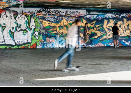 Skateboard nel South Bank undercroft con pareti ricoperte di graffiti. Foto Stock