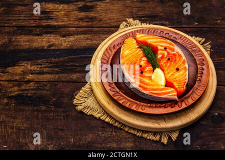 Trota norvegese cruda. Pezzi di pesce fresco, limone, aneto, pepe, sale. Vecchie tavole di legno di sfondo Foto Stock