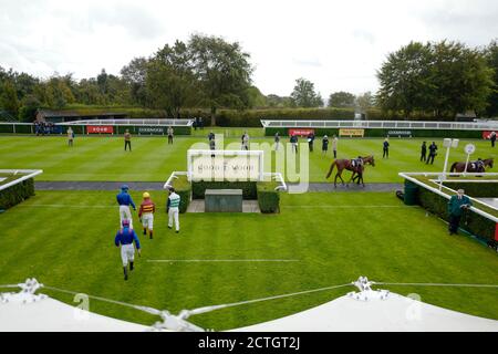 Una visione generale dei jockey mentre entrano nell'anello della parata per la prima corsa all'Ippodromo di Goodwood. Foto Stock