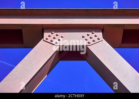 Trave in acciaio verniciata rosa di un ponte ad arco legato davanti ad un cielo blu, sfinestratura astratta Foto Stock