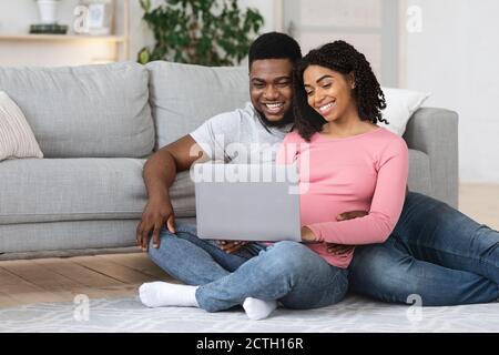 Amare la coppia afro-americana incinta usando il laptop a casa Foto Stock