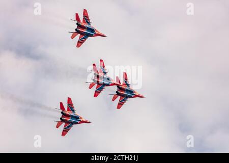 Barnaul, Russia - 19 settembre 2020: Un tiro a bassa angolazione dello squadrone da combattimento Strizhi MIG-29 che esegue acrobazie durante un aerostshow. Blu cielo nuvoloso come Foto Stock