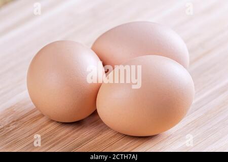 Uno sfondo di uova fresche di fattoria marrone su un legno tagliere Foto Stock