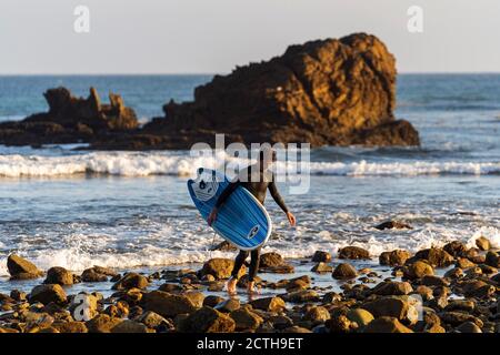 Malibu, California, Stati Uniti. 15 marzo 2019. Un surfista porta la sua tavola da surf come esiste una spiaggia rocciosa a Malibu. Credit: Ronen Tivony/SOPA Images/ZUMA Wire/Alamy Live News Foto Stock