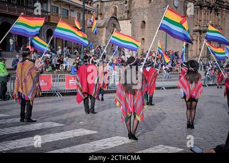 Da dietro, gli impiegati che portano bandiere arcobaleno di Cusco in una sfilata durante la festa del sole Inti Raymi'rata sul solstizio invernale, Cusco, Perù Foto Stock