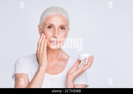 Ritratto di attraente donna che applica gel nutriente guardando la macchina fotografica indossando una t-shirt elegante e alla moda isolata su sfondo bianco Foto Stock
