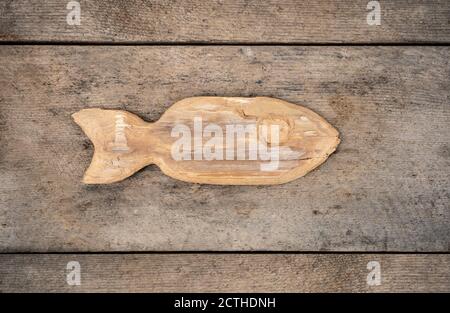 Pesce di legno intagliato a mano su sfondo di legno. Concetto per la pesca o l'arte popolare legno è vecchio e stagionato. Arte popolare Foto Stock