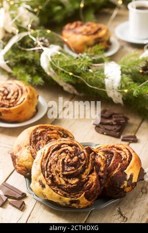 Lumaca muffin al cioccolato servito con il caffè sullo sfondo di una ghirlanda di rami di abete e coni. Stile rustico. Foto Stock