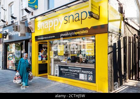 Una donna passa accanto a un ramo di Snappy Snaps a Camden High Street in un pomeriggio insolitamente caldo di fine settembre, Londra, Regno Unito Foto Stock