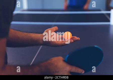 Un giovane gioca a ping pong. Tiene una palla e una racchetta nelle mani Foto Stock
