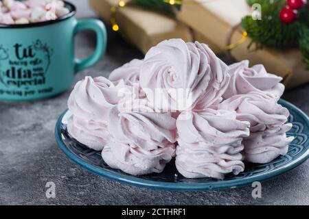 Delizioso dessert di natale con decorazioni natalizie. Marshmallow o zephyr fatti in casa su piatto e tazza di cioccolata calda con marshmallow su tavola grigia Foto Stock