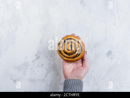 Concetto di pasticceria. Donna che tiene la pistola con i semi di papavero vista dall'alto, spazio di copia. Foto Stock