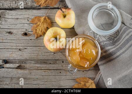 Marmellata di mele o salsa fatta in casa in vaso sul tavolo. Copia di sfondo rustico in legno, vista dall'alto. Foto Stock