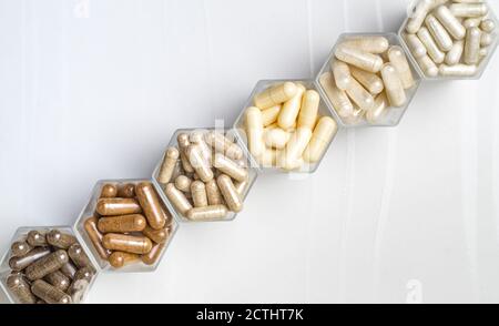 Varie capsule mediche a base di erbe ed omeopatiche in vasi esagonali la forma di nido d'ape Foto Stock