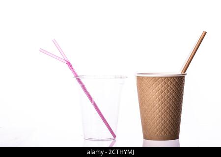 Plastica e materiali naturali. Cannucce a tazza in plastica trasparente e tazza di carta artigianale Foto Stock