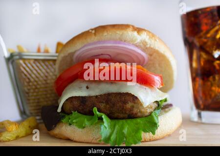 Cheeseburger con Fries e Cold Cola su tavola di legno, su sfondo bianco Foto Stock