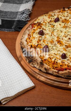 Pizza Chicken Catupiry sapore servito su una tavola di legno. A base di mozzarella, pollo, formaggio cremoso, olive e salsa di pomodoro rosso. Vetro di oliv Foto Stock