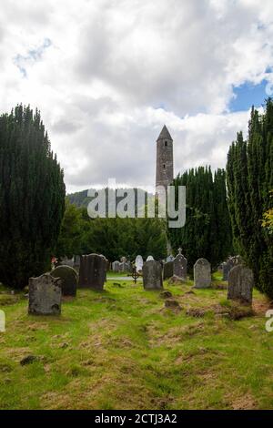 Un cimitero Glendalough con una torre rotonda Glendalough sullo sfondo Foto Stock