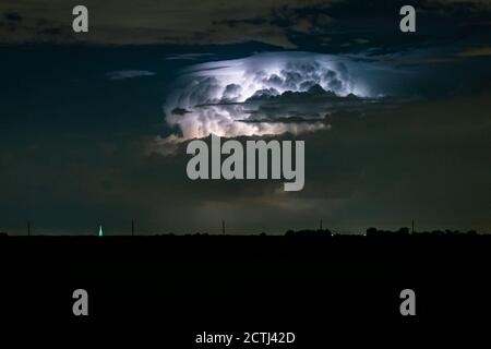 La tempesta supercella distante è illuminata da un fulmine di notte Foto Stock