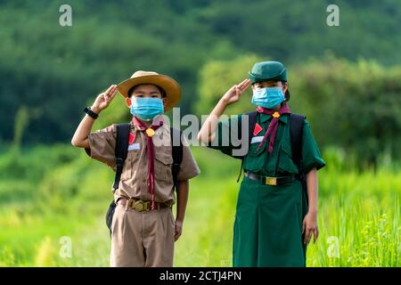 Asian Scout indossare una maschera e Mostra rispetto, nuova normalità Foto Stock