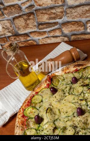 Deliziosa pizza italiana vegetariana, con salsa di pomodori, peperoni, olive e zucchine su sfondo di tavola in legno. Testo in portoghese: Serenità Foto Stock