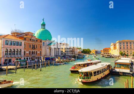 Venezia, Italia, 13 settembre 2019: Paesaggio urbano veneziano con yacht e vaporetti che navigano lungo il Canal Grande, Chiesa di San Simeone piccolo sul lungomare di Santa Croce, sfondo blu del cielo, Regione Veneto Foto Stock