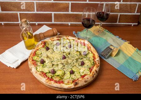 Deliziosa pizza italiana vegetariana, con salsa di pomodori, peperoni, olive e zucchine su tavola di legno. Foto Stock