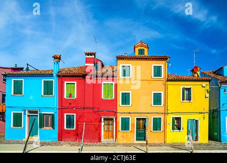 Fila di case colorate sull'isola di Burano. Edifici multicolori su argine di fondamenta canale d'acqua, cielo azzurro in giornata di sole, provincia di Venezia, Regione Veneto, Italia settentrionale. Burano cartolina Foto Stock