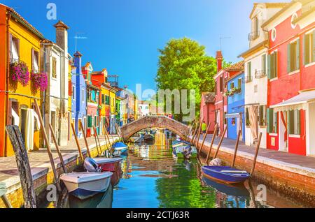 Case colorate dell'isola di Burano. Edifici multicolore su argine di fondamenta, stretto canale d'acqua con barche da pesca e ponte di pietra, provincia di Venezia, Regione Veneto, Italia. Burano cartolina Foto Stock