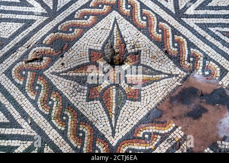 Piastrelle a mosaico di una Villa Romana nel Sussex Occidentale, Inghilterra. Mostra una stella composta da piastrelle rosse, gialle, bianche e nere Foto Stock
