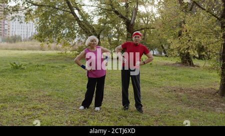 Coppia anziana attiva di 80 anni. Uomo e donna caucasici facendo mattina esercizi di allenamento fisico stretching nel parco. Fitness nonni famiglia tempo libero. Stile di vita sano Foto Stock