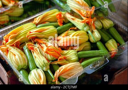 fiori di zucchine e ovaie in scatola in vendita. Raccogliere deliziose zucchine per cucinare in pastella Foto Stock