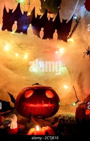 Halloween jack o lanterna party decorazione scolpito zucca con spaventoso viso con luce in una stanza di festa scura con ragni decorativi, web, pipistrelli e. Foto Stock