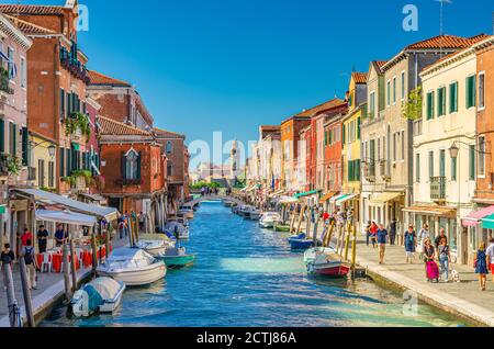 Murano, Italia, 14 settembre 2019: ponte attraverso il canale d'acqua, barche e barche a motore, colorati edifici tradizionali, Laguna Veneziana, Regione Veneto. San Michele in Isola Chiesa cattolica background Foto Stock