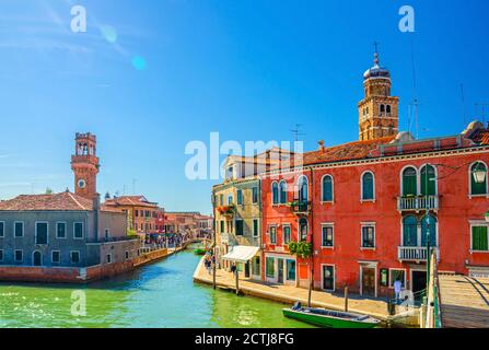 Le isole di Murano con ponte sul canale, barche e barche a motore, colorati edifici tradizionali, Torre dell'Orologio, Regione Veneto, Italia settentrionale. Paesaggio urbano da cartolina di Murano. Foto Stock