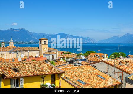Veduta panoramica aerea della città di Desenzano del Garda con campanile della chiesa del Duomo di Santa Maria Maddalena, tetti in tegole rosse, lago di Garda, catena montuosa, Lombardia, Italia settentrionale Foto Stock