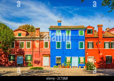 Case colorate dell'isola di Burano. Edifici multicolore in piccola piazza acciottolata, cielo blu in piena estate, provincia di Venezia, Regione Veneto, Italia settentrionale. Burano cartolina Foto Stock