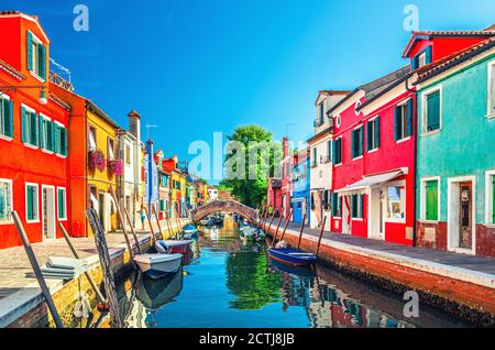 Case colorate dell'isola di Burano. Edifici multicolore su argine di fondamenta, stretto canale d'acqua con barche da pesca e ponte di pietra, provincia di Venezia, Regione Veneto, Italia. Burano cartolina Foto Stock