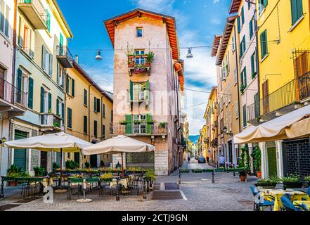 Tradizionale edificio colorato con balconi e finestre in tipica strada italiana, tavoli e tenda di ristorante di strada, centro storico di Brescia, Lombardia, Italia settentrionale Foto Stock