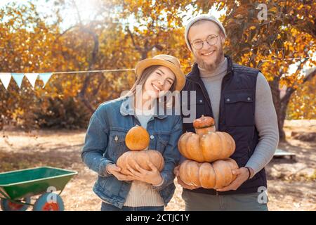 Concetto di preparazione di Halloween. Giovane coppia in piedi in giardino con zucche in posa sorridente allegro Foto Stock