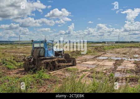 Un vecchio trattore cingolato sullo sfondo del paesaggio. Macchine agricole sul campo Foto Stock