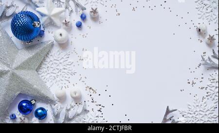 Natale e Capodanno stelle bianche, fiocchi di neve e palline blu di Natale e decorazioni tra scintille su uno sfondo bianco, vista dall'alto, disposizione piatta, copia centro benessere Foto Stock