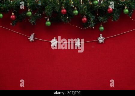 Clothespins di Natale su una corda e un posto per un Iscrizione su fondo di tessuto rosso con rami di albero di Natale e le palle Foto Stock