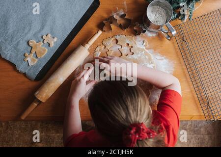 Giovane ragazza che taglia l'impasto di pan di zenzero su un tavolo di legno Foto Stock