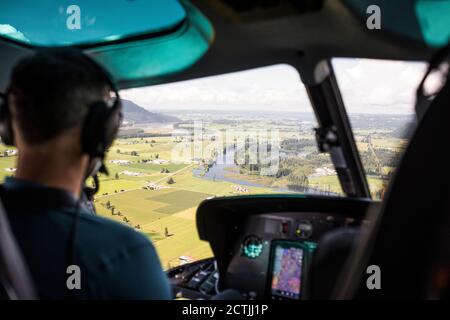 Pilota in elicottero che guarda verso i terreni agricoli della Fraser Valley. Foto Stock