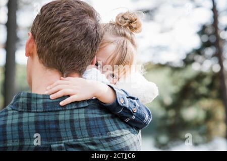 bambina che viene portata dal suo papà guardando dietro di lei aspetto accogliente Foto Stock