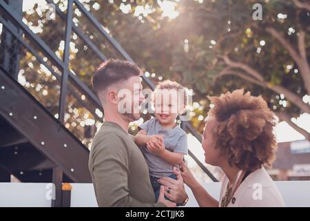 Papà che tiene il bambino ragazzo e mamma cercando di farlo ridere Foto Stock