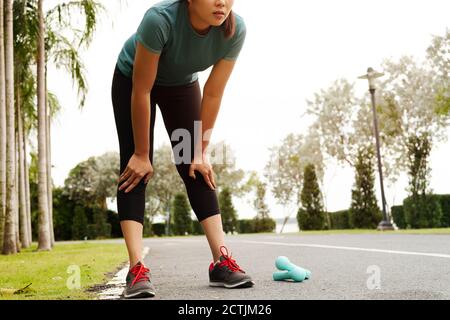 Stanco donna fitness di prendere un periodo di riposo dopo il duro allenamento sul parco Foto Stock